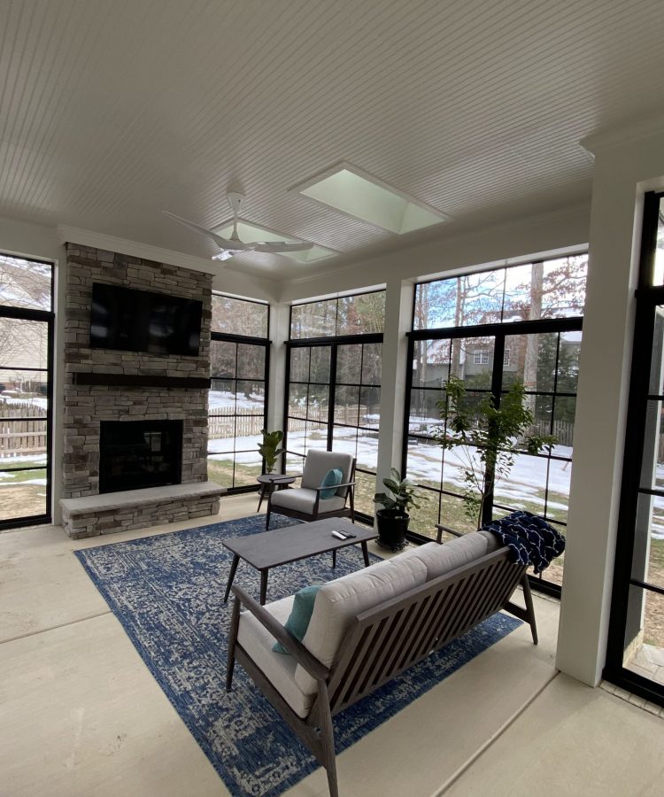 After photo of enclosed porch with fireplace and black Oasis 4-Track Enclosure installed by Turnkey Porch Enclosures.